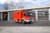 Ein rotes Flugeinsatzfahrzeug steht bei Tageslicht vor dem Gebäude der Berufsfeuerwehr Innsbruck.