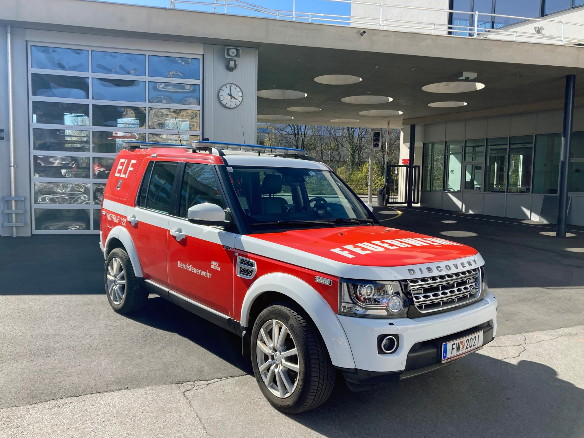 Ein rotes Einsatzleitfahrzeug mit Allradantrieb steht bei Tageslicht vor dem Gebäude der Berufsfeuerwehr Innsbruck.