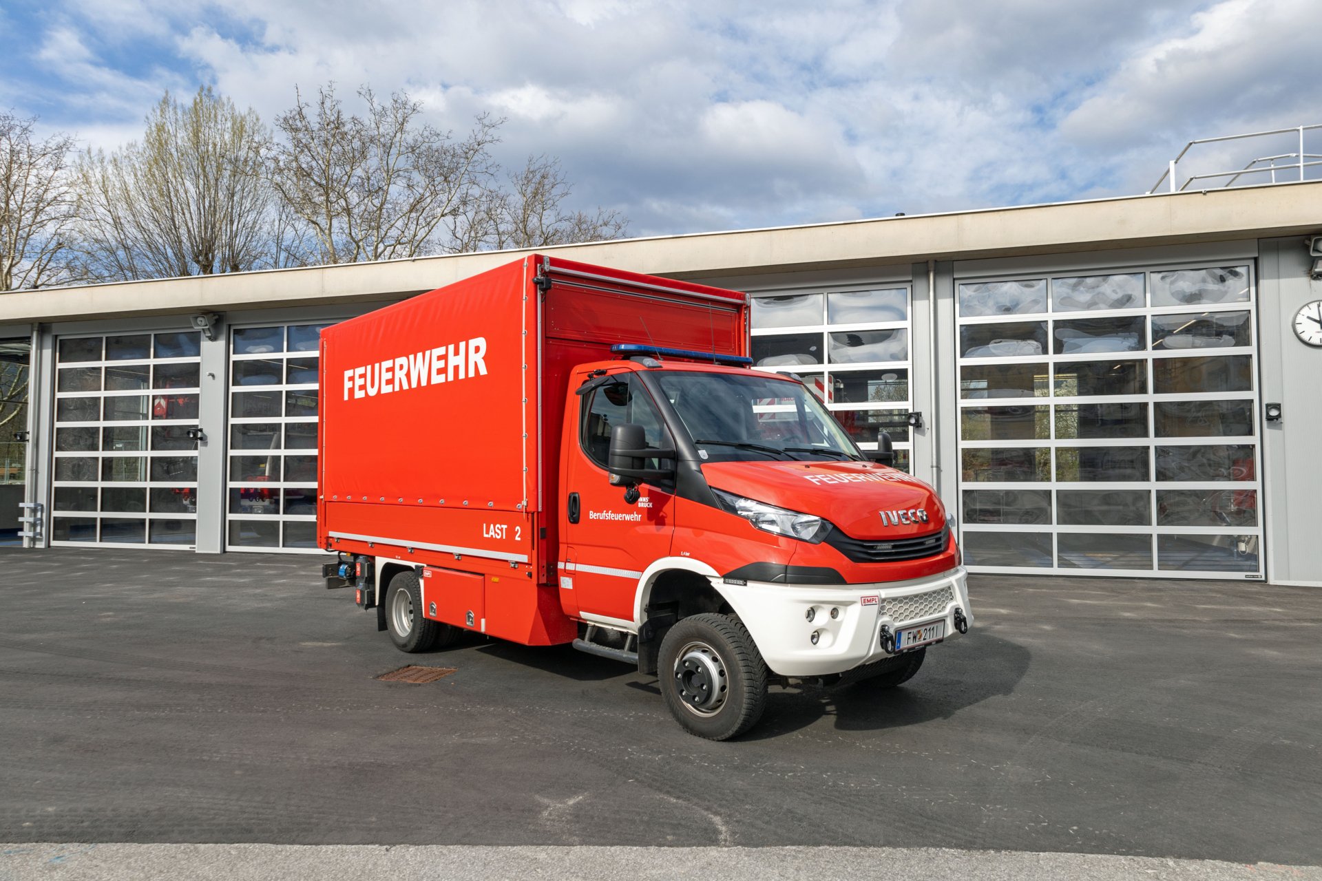 Ein rotes Lastfahrzeug steht bei Tageslicht vor dem Gebäude der Berufsfeuerwehr Innsbruck.