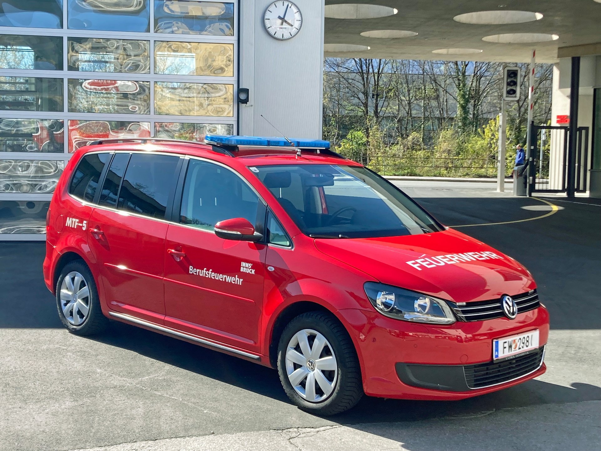 Ein rotes Mannschaftstransportfahrzeug steht bei Tageslicht vor dem Gebäude der Berufsfeuerwehr Innsbruck.