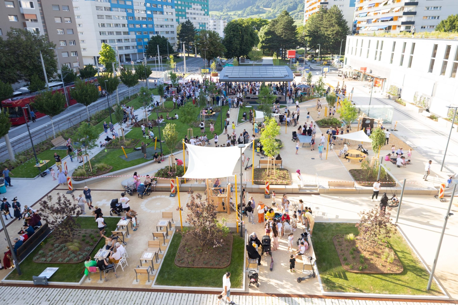Luftbild vom neu eröffneten Coolymp mit Grünflächen, vielen Menschen und einer Tram auf der linken Seite