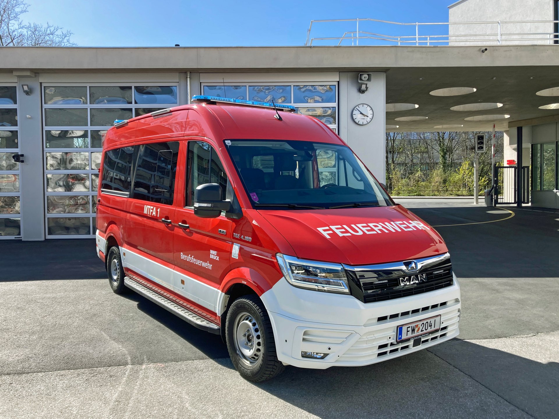 Ein rotes Mannschaftstransportfahrzeug mit Allradantrieb steht bei Tageslicht vor dem Gebäude der Berufsfeuerwehr Innsbruck.