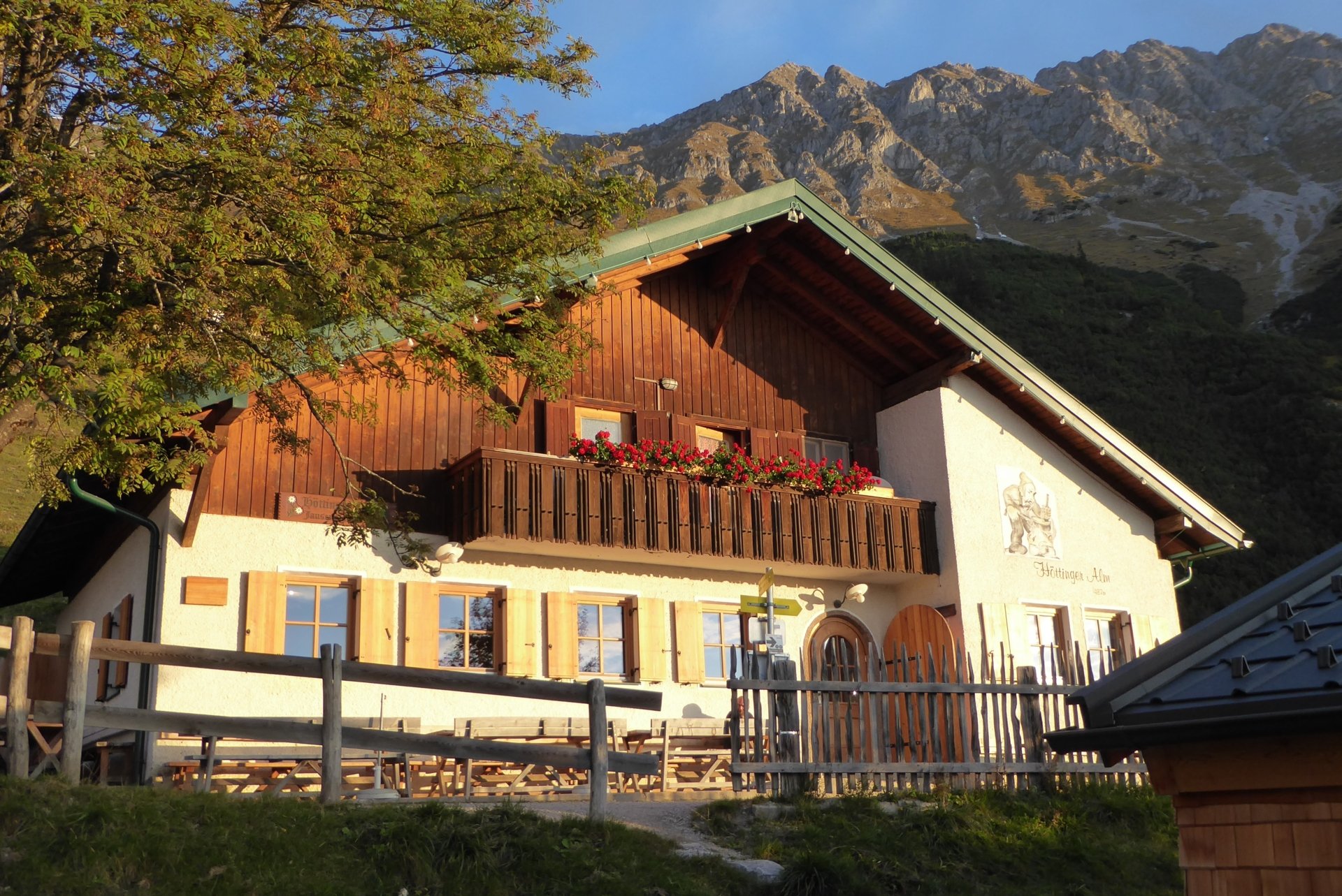 Die Höttinger Alm bei blauem Himmel und Bergen im Hintergrund.