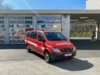Ein rotes Höhenrettungsfahrzeug steht bei Tageslicht vor dem Gebäude der Berufsfeuerwehr Innsbruck.