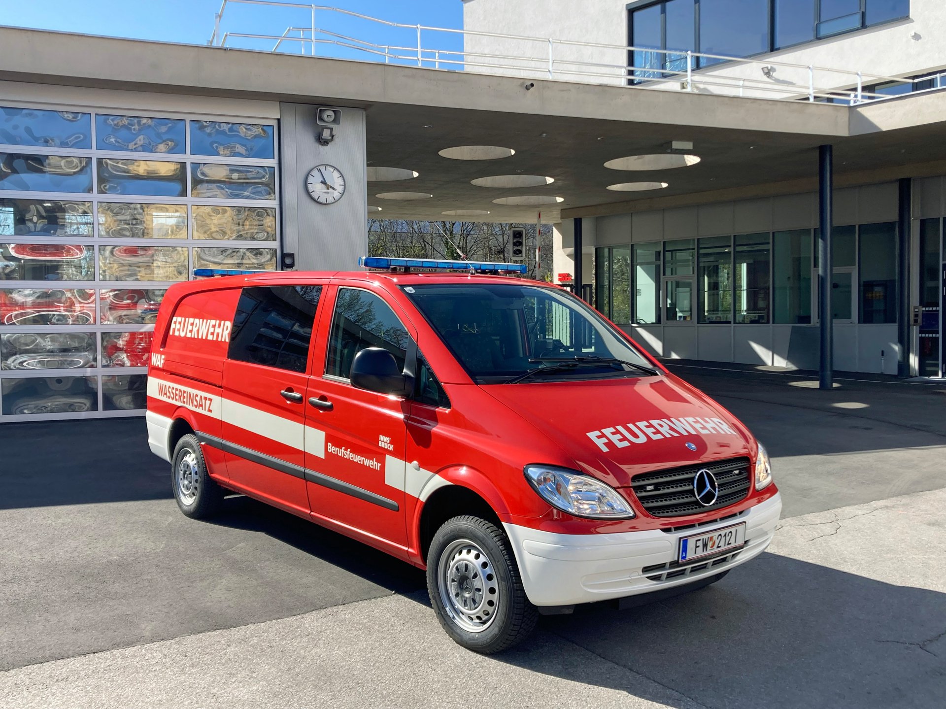 Ein rotes Wasserfahrzeug steht bei Tageslicht vor dem Gebäude der Berufsfeuerwehr Innsbruck.