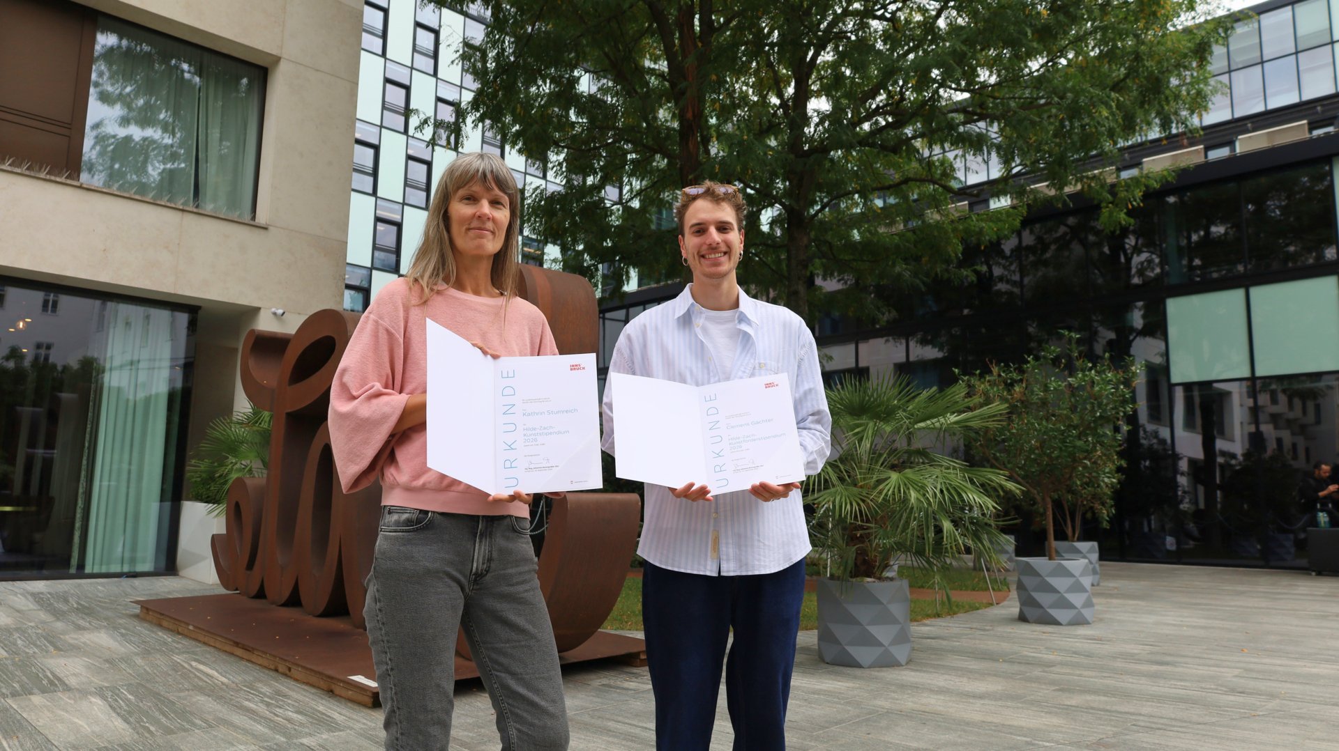 Kathrin Stumreich und Clemens Gächter präsentieren ihre Urkunden für das Hilde-Zach-Kunststipendium 2026.