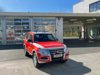 Ein rotes Transportfahrzeug mit Allradantrieb steht bei Tageslicht vor dem Gebäude der Berufsfeuerwehr Innsbruck.