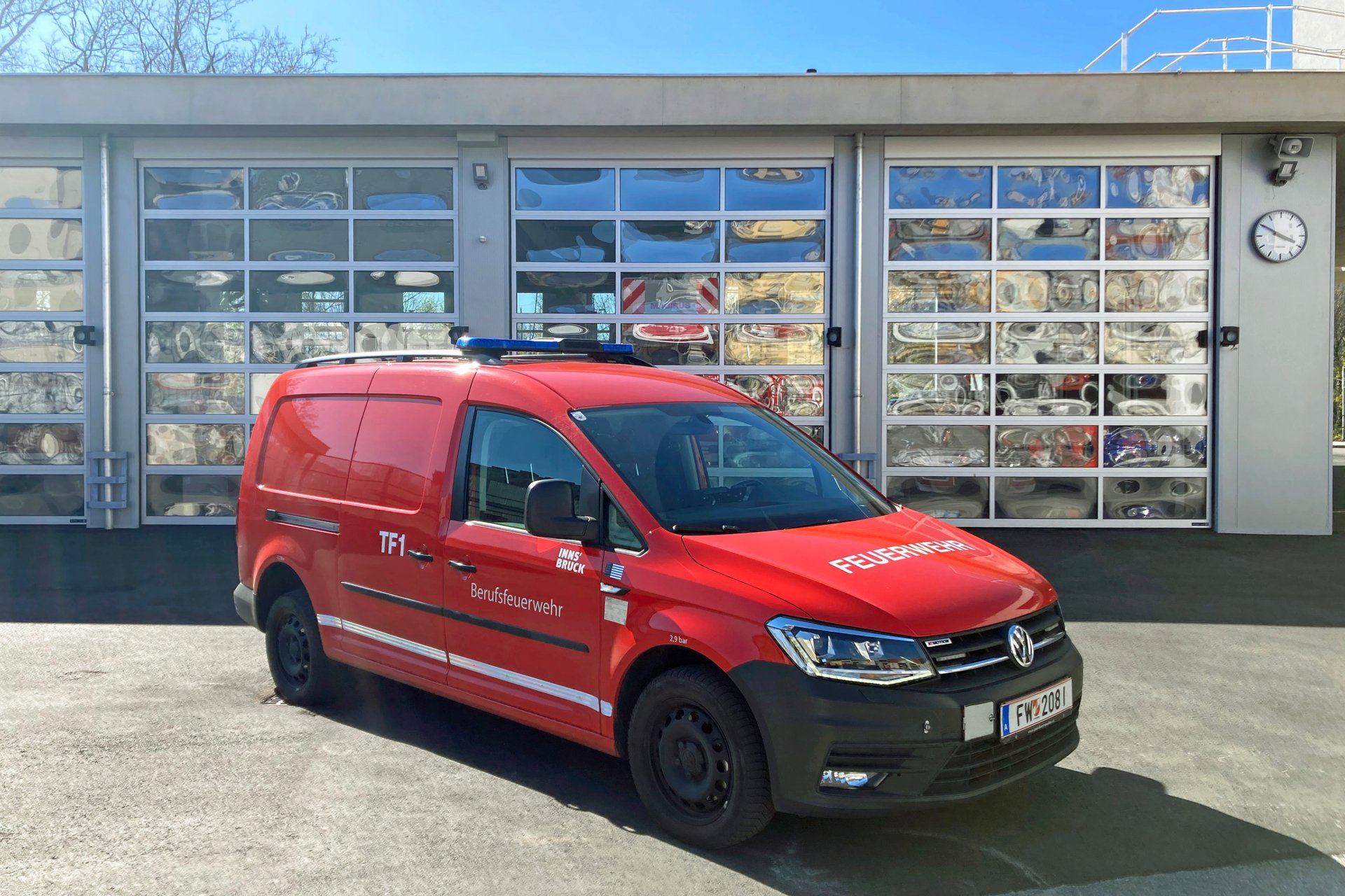 Ein rotes Transportfahrzeug mit Allradantrieb steht bei Tageslicht vor dem Gebäude der Berufsfeuerwehr Innsbruck.