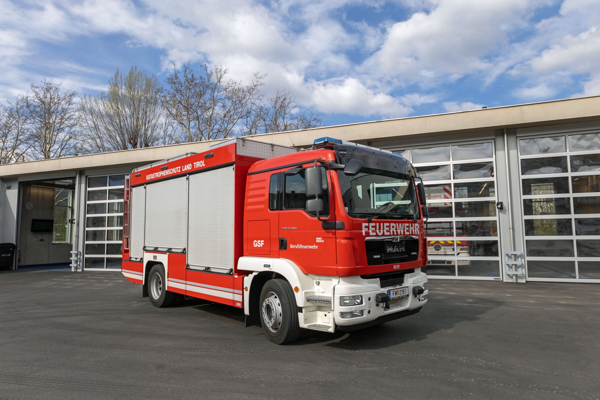 Ein rotes Gefährliche-Stoffe-Fahrzeug steht bei Tageslicht vor dem Gebäude der Berufsfeuerwehr Innsbruck.