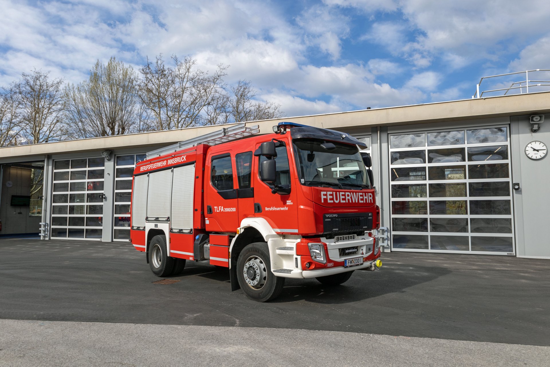Ein rotes Tanklöschfahrzeug mit Allradantrieb steht bei Tageslicht vor dem Gebäude der Berufsfeuerwehr Innsbruck.