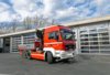 Ein roter Lastkraftwagen mit Kran steht bei Tageslicht vor dem Gebäude der Berufsfeuerwehr Innsbruck.