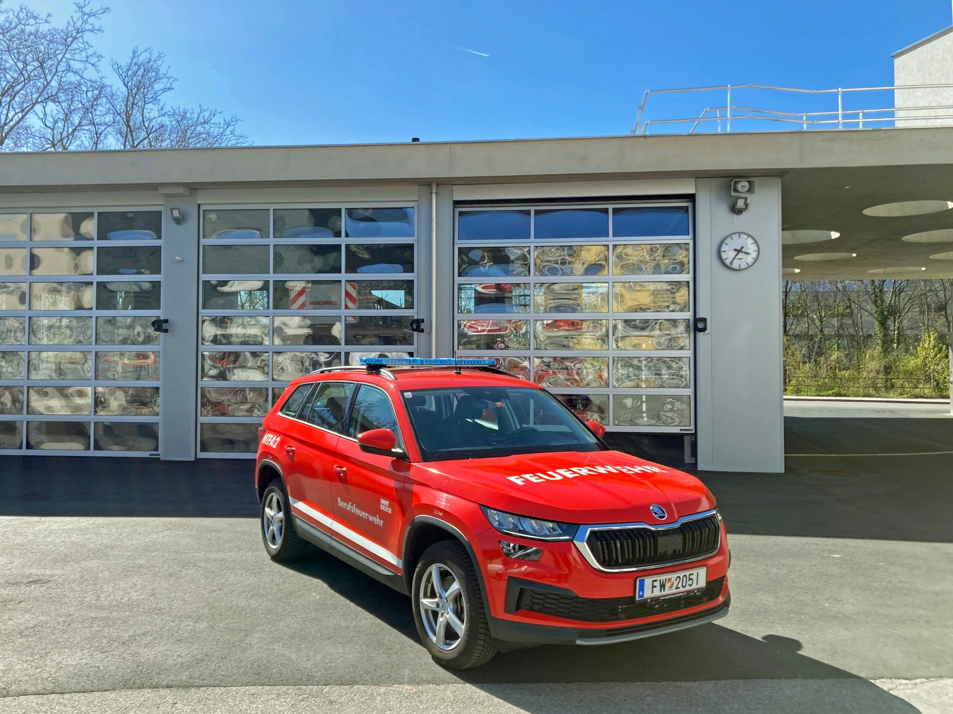 Ein rotes Mannschaftstransportfahrzeug mit Allradantrieb steht bei Tageslicht vor dem Gebäude der Berufsfeuerwehr Innsbruck.