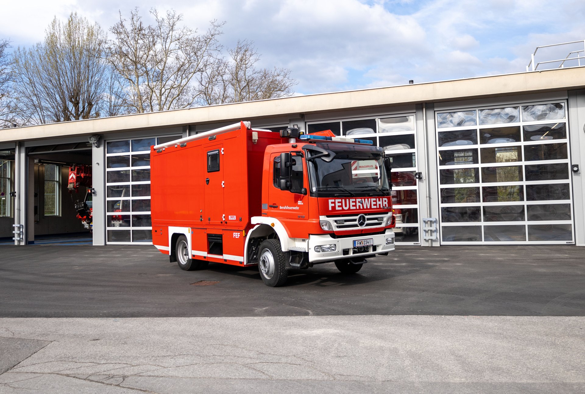Ein rotes Flugeinsatzfahrzeug steht bei Tageslicht vor dem Gebäude der Berufsfeuerwehr Innsbruck.