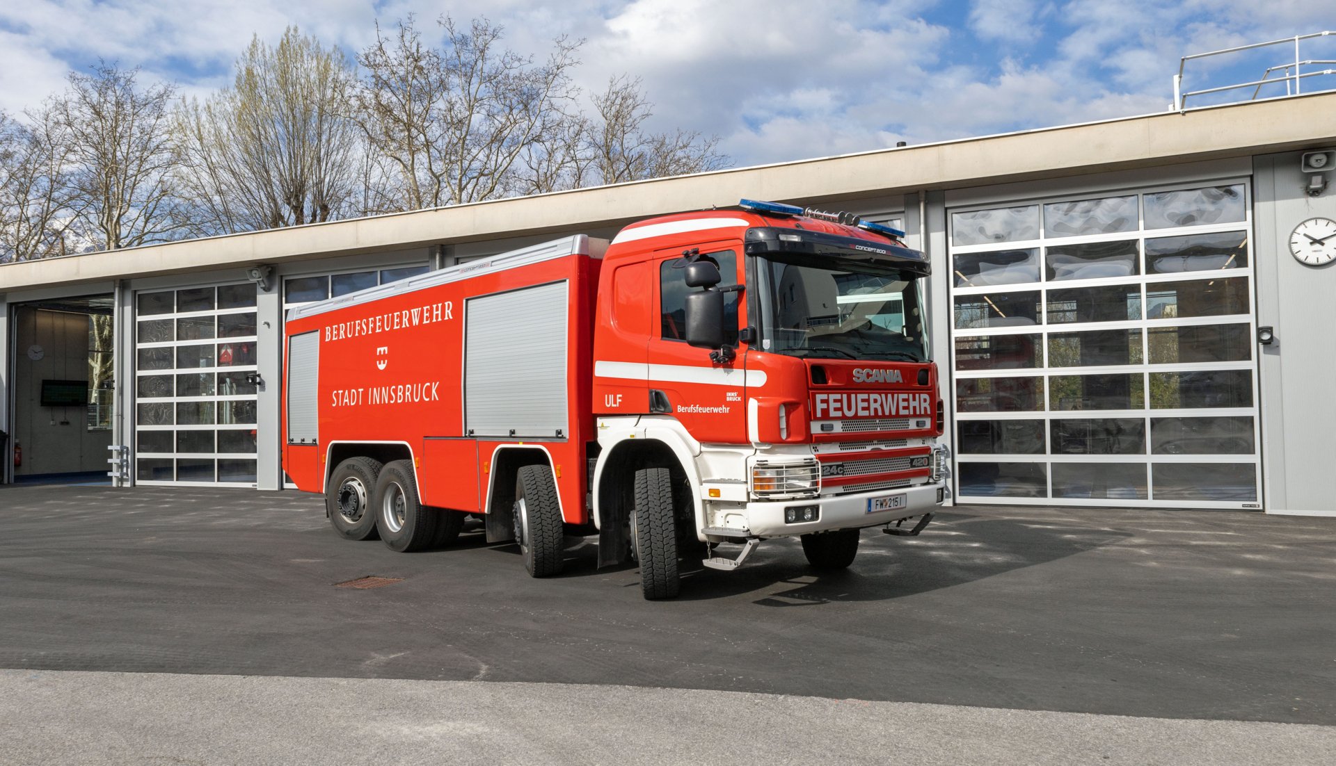 Ein rotes Universallöschfahrzeug steht bei Tageslicht vor dem Gebäude der Berufsfeuerwehr Innsbruck.