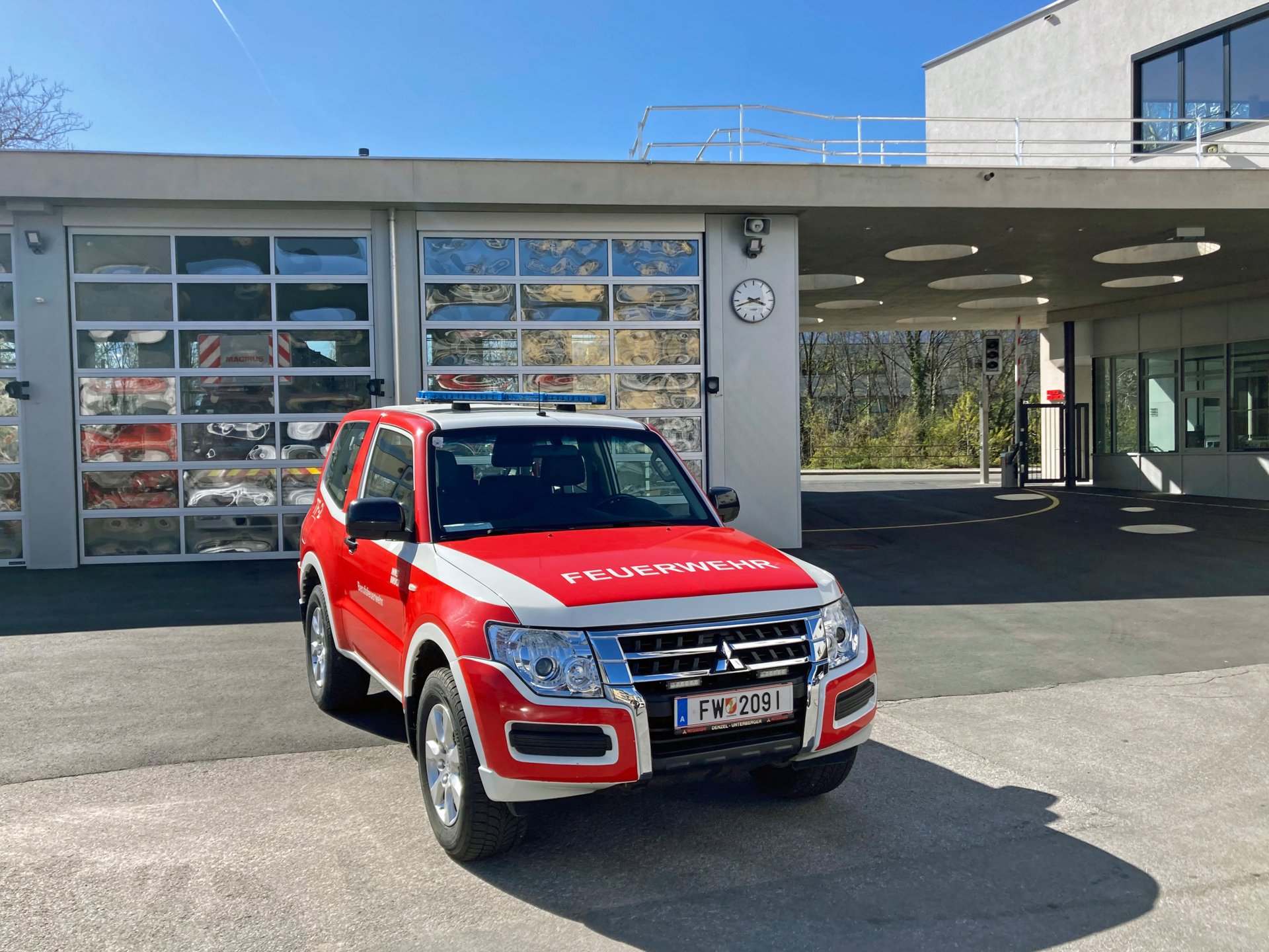 Ein rotes Transportfahrzeug mit Allradantrieb steht bei Tageslicht vor dem Gebäude der Berufsfeuerwehr Innsbruck.