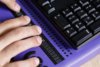 Ein Ausschnitt einer Tastatur mit Braillzeile, auf der mit 4 Fingern gefühlt wird.