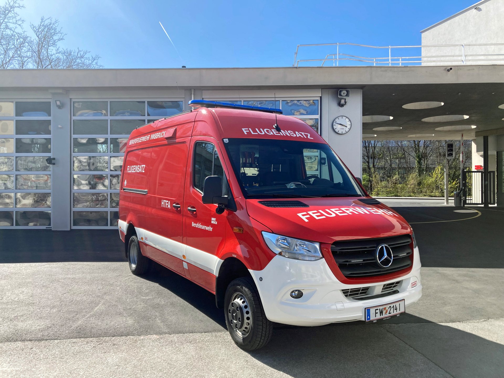Ein rotes Hubschraubertankfahrzeug steht bei Tageslicht vor dem Gebäude der Berufsfeuerwehr Innsbruck.