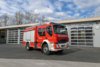 Ein rotes Tanklöschfahrzeug mit Allradantrieb steht bei Tageslicht vor dem Gebäude der Berufsfeuerwehr Innsbruck.