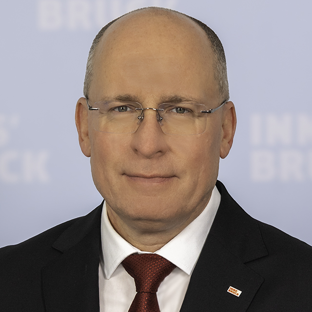 Magistratsdirektor Stephan Crepaz im Anzug mit roter Krawatte und Innsbruck-Pin am Revers.